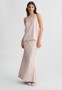 Abito senza maniche color rosa cipria con gonna fluida, realizzato in tessuto morbido. Presenta una vestibilità rilassata e spacchi laterali per una facile movimentazione.