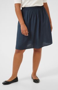 Navy blue, knee-length skirt made of lightweight fabric with an elastic waistband. Worn with black flat shoes featuring a bow detail.