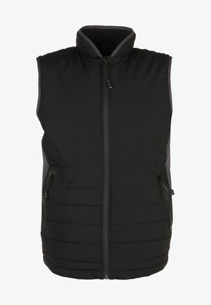 Veste noire matelassée portée sur un t-shirt gris à manches longues, associée à un pantalon noir et des baskets grises avec des accents roses.