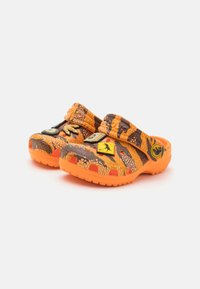 Orange og brune mønstrede træsko med en struktureret overflade, justerbare remme og sorte accenter med logoer på fronten.