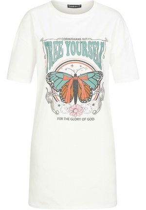Camiseta de algodón blanca con estampado gráfico que presenta una mariposa en tonos verde azulado y naranja, acentos florales y el texto "LIBÉRATE" en la parte superior.