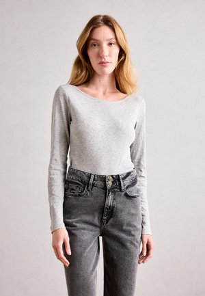 Gray long-sleeve top made of soft fabric, paired with high-waisted black denim jeans featuring two-button closure and front pockets.