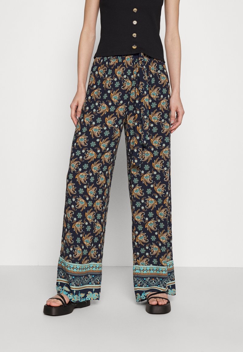 Námořnické kalhoty s širokými nohavicemi a květinovými a paisley vzory v oranžové a tyrkysové barvě. Dokončeno s vzorovaným lemem a volným střihem.