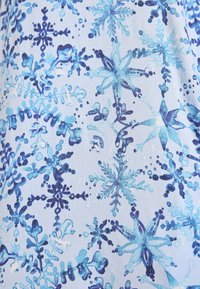 Tessuto blu chiaro con vari motivi di fiocchi di neve in diverse nuance di blu, con dettagli e trame intricate che illustrano il design ghiacciato.