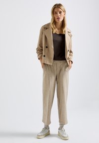 Beige cropped takki, tumma ruskea yläosa, vaaleat ruutukuosiset housut ja valkoiset tennarit, joissa on harmaita yksityiskohtia. Sileät tekstuurit ja rento istuvuus.