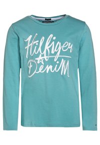 Turkusowa koszula z długim rękawem z bawełny, z białym napisem "Hilfiger Denim" na przodzie. Okrągły dekolt i luźny krój.
