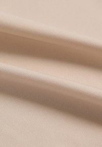 Beige tkanina s jemnou diagonální strukturou, s měkkými, hladkými záhyby. Tenký a lehký vzhled bez viditelných vzorů.