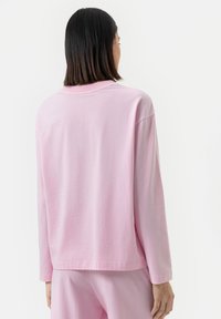 Roze langemouwen shirt, gemaakt van zachte katoen, met een relaxte pasvorm en ronde halslijn, vanachter afgebeeld. Gladde textuur, minimalistisch ontwerp.