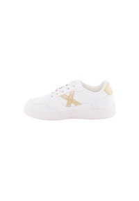 Zapatilla deportiva blanca con una superficie de cuero suave, que presenta un acento de color beige claro y costuras en contraste. Diseño con cordones y un collar acolchado.