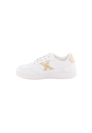 Zapatilla deportiva blanca con una superficie de cuero suave, que presenta un acento de color beige claro y costuras en contraste. Diseño con cordones y un collar acolchado.