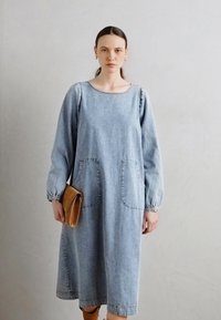 Jeanskleid mit langen Puffärmeln, rundem Ausschnitt und zwei Fronttaschen. Hellblaue Farbe mit lässiger Passform und gerafften Ärmelabschlüssen.
