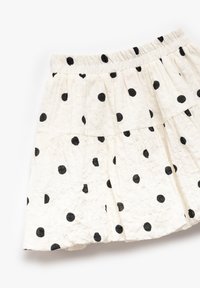 Falda blanca de Volantes con lunares negros. Cintura elástica, tejido texturizado y detalle de dobladillo con volantes. La longitud es por encima de la rodilla.
