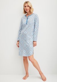 Abito da notte blu a fantasia con maniche lunghe, un piccolo scollo frontale e fessure laterali. Presenta disegni floreali in tonalità di blu chiaro e scuro.