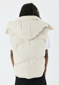 Licht beige puffer vest met een gestructureerd ruitpatroon, voorzien van een grote capuchon en een losse pasvorm. Zacht materiaal en zichtbare stiksels.