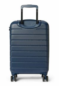Valise coque dure bleu marine avec une surface texturée, des rainures verticales, une poignée rétractable et quatre roues noires pour la mobilité.
