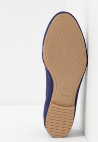 Chaussure en tissu violet avec semelle en caoutchouc texturé. Présente un orteil lisse et arrondi, ainsi que des détails cousus sur le côté. Taille 37.