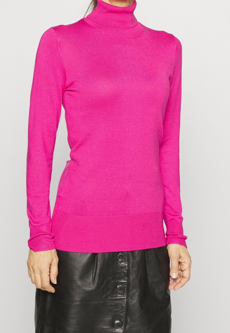 Fitted turtleneck sweater in vibrant pink, made of soft, lightweight material. Long sleeves and ribbed cuffs and hem. Worn with a black leather skirt.