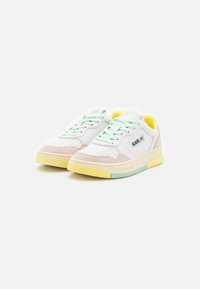 Białe skórzane sneakersy z mięty w sznurówkach, z zamszowymi akcentami w kolorze kremowym i jasnym żółtym. Posiadają perforowaną część palców oraz kontrastowe logo.