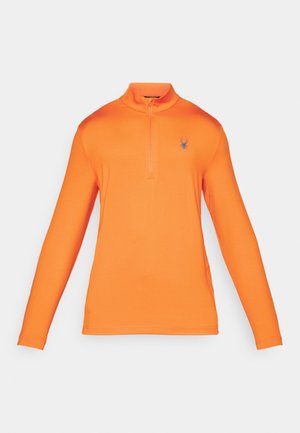 Pull-over orange à manches longues avec un col zippé, fabriqué en tissu lisse et extensible. Présente un petit logo d'araignée bleue sur la poitrine.