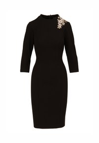 Robe noire près du corps avec des manches trois-quarts, décolleté rond et une décoration florale sur l'épaule gauche.