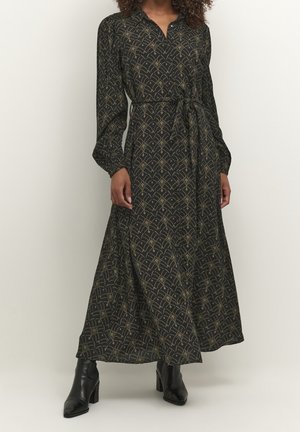 Czarna sukienka maxi z długimi rękawami, złotym abstrakcyjnym wzorem, z przodu na guziki, wiązana w talii, noszona z czarnymi botkami na obcasie.