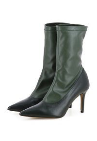 Bottes stilettos à bout pointu avec un design en deux matières : tige supérieure verte en matériau doux et bout en cuir noir, présentant une silhouette de cheville ajustée et un talon fin.