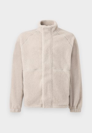 Fleece jacket in light beige with a high collar, long sleeves, and a soft textured surface. Features two front pockets and a straight cut.