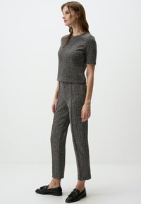 Set coordinato grigio in maglia composto da una maglietta a maniche corte e pantaloni slim-fit, caratterizzato da un sottile motivo testurizzato e scarpe mocassino nere.