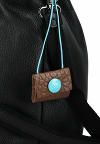 Lo zaino in pelle nera presenta una superficie testurizzata e accessori in argento. L'etichetta marrone con bottone blu aggiunge contrasto e dettagli.