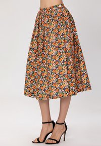 Jupe midi florale avec un fond noir, présentant des fleurs vibrantes orange, rose et verte. Taille élastique et design fluide.