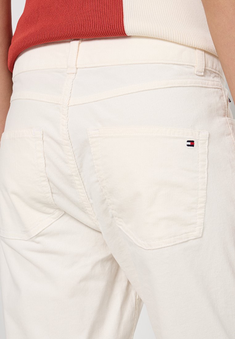 Białe spodnie z korduroy z dwoma tylkimi kieszeniami oraz małym logo w kolorze czerwonym, białym i niebieskim na prawej kieszeni.