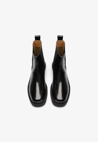 Botine negre din piele cu un finisaj neted și lucios, având un interior maro, panouri laterale elastice și tab-uri pentru o încălțare ușoară.