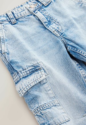 Light blue denim cargo pants with multiple pockets and visible stitching. Fabric shows a faded texture with a relaxed fit and button closure.