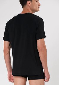 Czarny t-shirt z krótkim rękawem, wykonany z gładkiego materiału. Posiada okrągły dekolt i luźny krój, z widocznymi szwami na rękawach.
