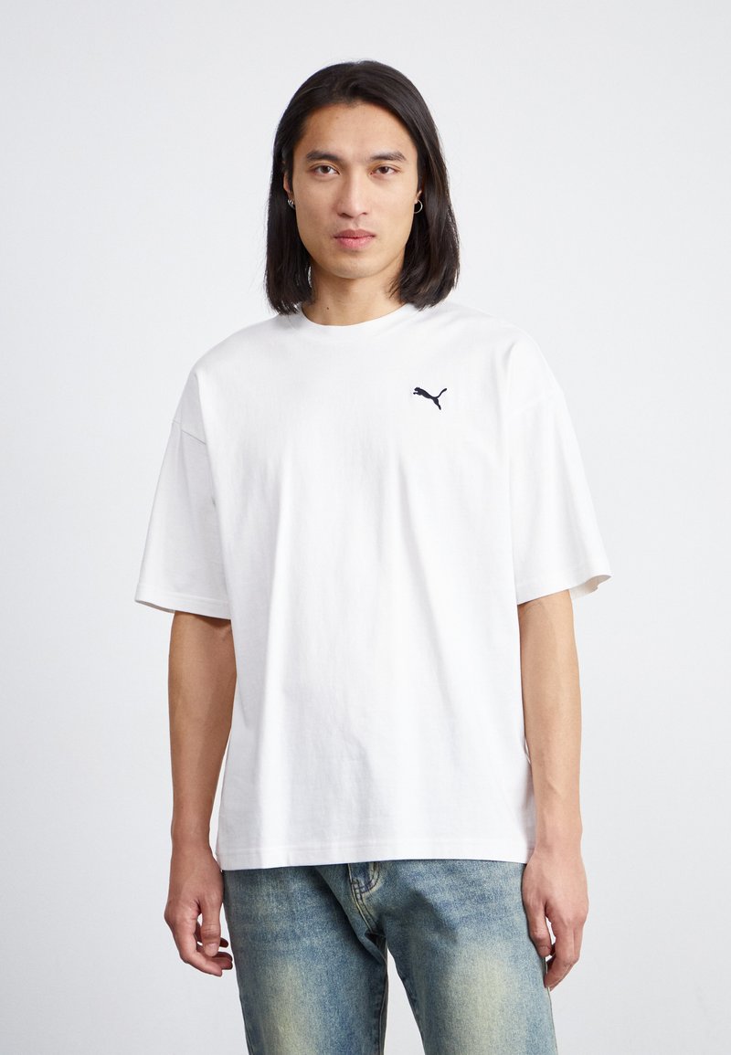 Tricou alb din bumbac, cu un croi lejer, maneci scurte și un logo Puma negru pe pieptul stâng. Material ușor texturat.