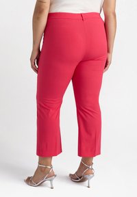 Rosa cropped byxor gjorda av ett mjukt, stretchigt tyg med resårmidja. Parat med silverfärgade strapsandaler.