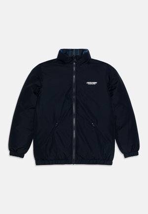 Juodas nailono švarkas su aukštu apykakle, užtrauktuku priekinėje dalyje, elastingomis rankovėmis ir dviem šoninėmis kišenėmis. Yra mėlynas raštuotas pamušalas ir baltas logotipas.