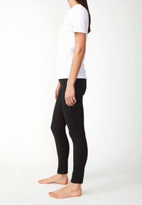 Bílá bavlněná tričko v kombinaci s černými skinny džíny. Tričko má krátké rukávy, zatímco džíny jsou přiléhavé a elastické.