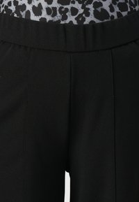 Black trousers with a smooth texture, featuring a wide elastic waistband and subtle pleats along the front for added detail.