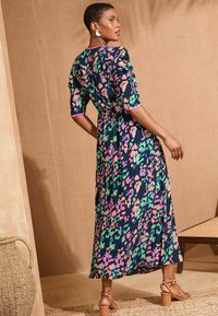 Maxi obleka v mornarsko modri barvi s pisanimi abstraktnimi vzorci v roza, zeleni in modri. Ima kratke naborke na rokavih in zategnjen pas.