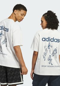Bílá bavlněná tričko s modrou potiskem designem basketbalistů na zadní straně, s textem "adidas" nahoře a "SPORT DESIGN STUDIO" dole.