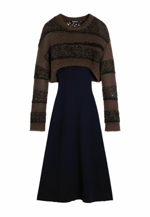 Brown and black striped cropped knit sweater paired with a high-waisted, long black A-line skirt dress.