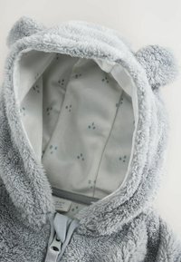 Szary polarowy hoodie dla niemowląt z uszami niedźwiedzia, z miękką podszewką wewnętrzną w wzór łap oraz zapięciem na zamek z przodu.