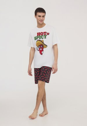 Maglietta grafica bianca con la scritta "HOT & SPICY" e un personaggio di peperoncino; pantaloni corti neri con motivo di peperoncini rossi; vestibilità comoda.