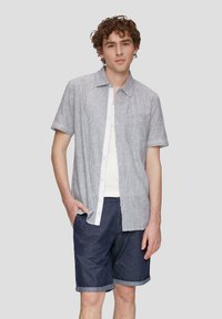 Korte mouwen, lichtblauwe gespikkelde overhemden met een witte plooi en zak, gecombineerd met donkere opgerolde denimshorts.