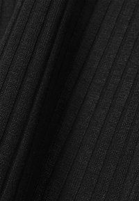 Svart ribbad tyg med en texturerad yta, med vertikala ränder. Materialet verkar mjukt med en lätt glans. Lättviktigt och flexibelt.