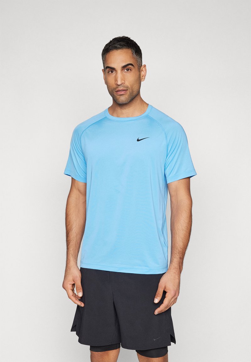 Hele sinine Nike'i sportwear shirt lühikeste varrukatega, ümmarguse kaelusega ja musta logoga rinnal, koos mustade lühikeste pükstega.