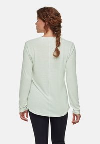 Jasnozielona koszula z długim rękawem, z zakrzywionym hemem, teksturowany materiał i pionowe przeszycie z tyłu. Nosić na czarnych legginsach.