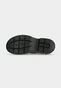 Semelle de chaussure en caoutchouc noir avec des motifs de crampons profonds et les chiffres 8, E et 1 embossés au-dessous.