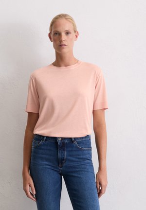 T-shirt rose clair à manches courtes avec un col rond, en tissu doux, associé à un jean en denim bleu foncé. Design simple et classique.